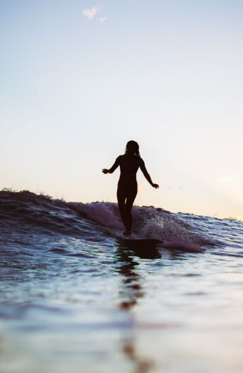 夕暮れの波に乗るサーファーのシルエット