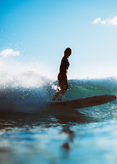ティールブルーの波に乗るサーファーのシルエット