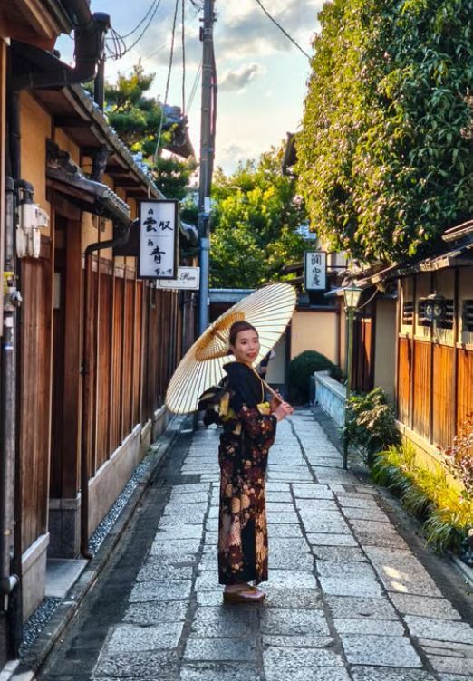 石畳の路地を和傘を差して歩く着物姿