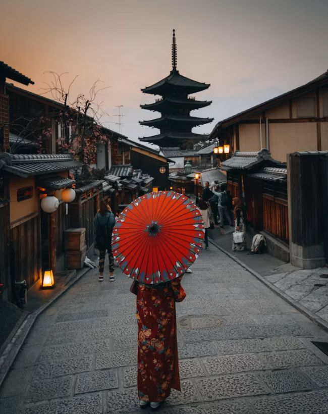 朱色の番傘を差して石畳の参道を歩く姿